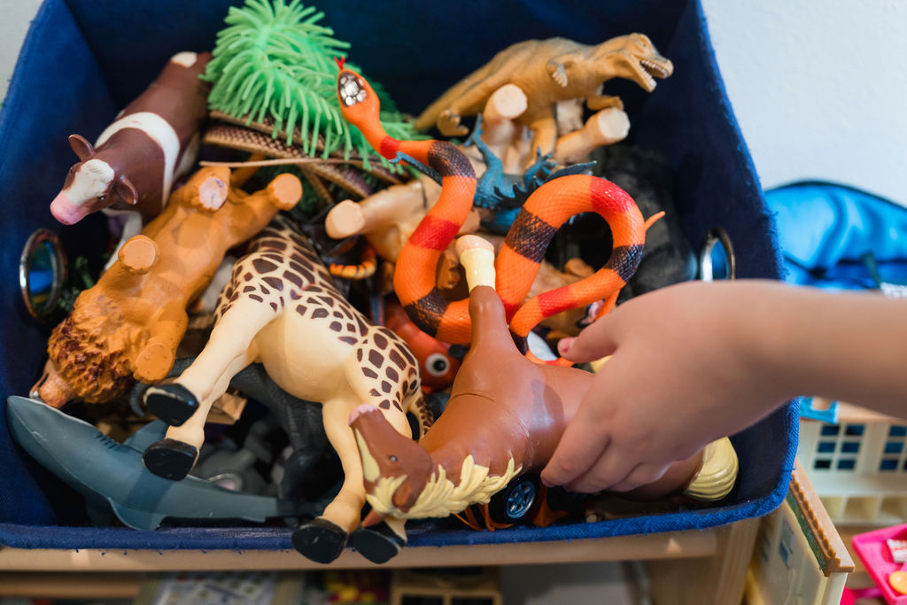 A child's hand reaching into a box of toys